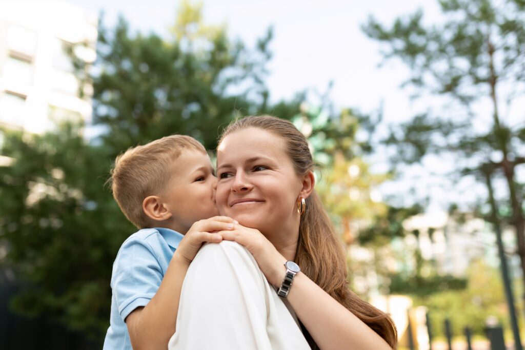 A mother smiles warmly as her son cuddles close