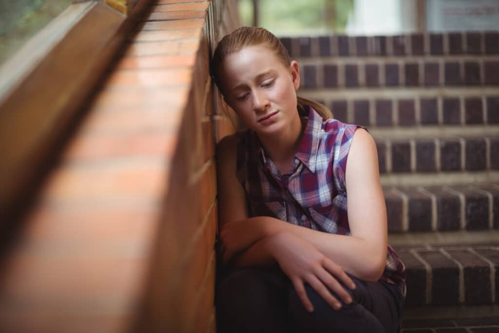 Sad schoolgirl sitting alone