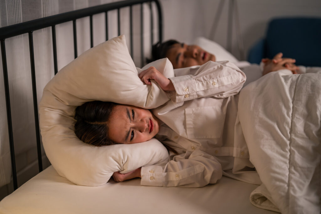 Asian woman feel frustrated from husband snoring while sleep