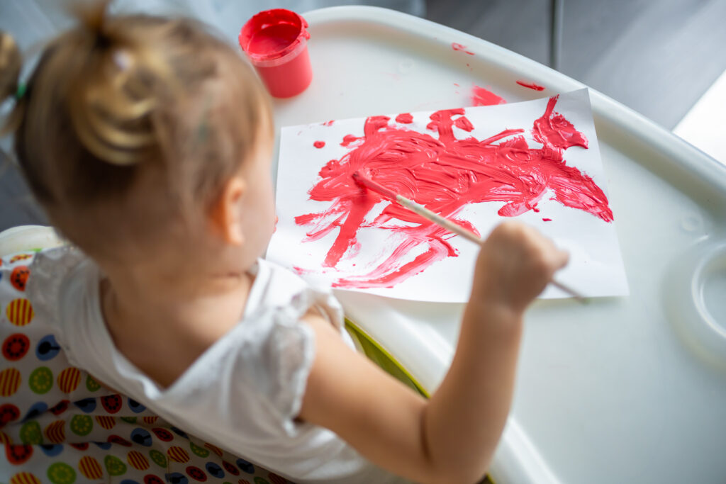 Cute little girl painting with brushes at home