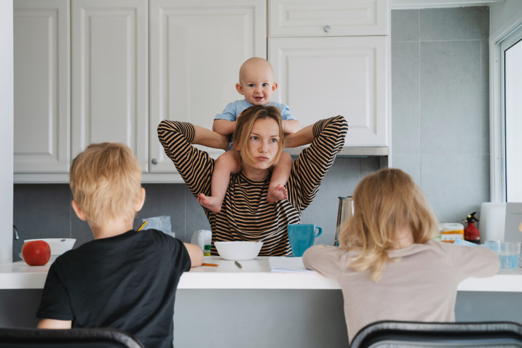 Young exhausted woman with three children at home