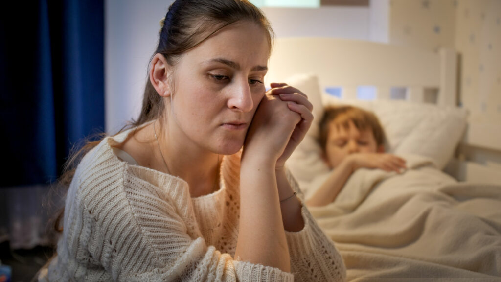 Young mother sitting next to bed