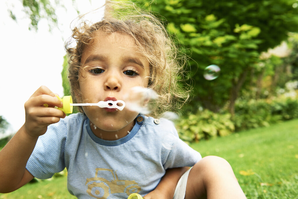 cute girl blowing bubbles in garden