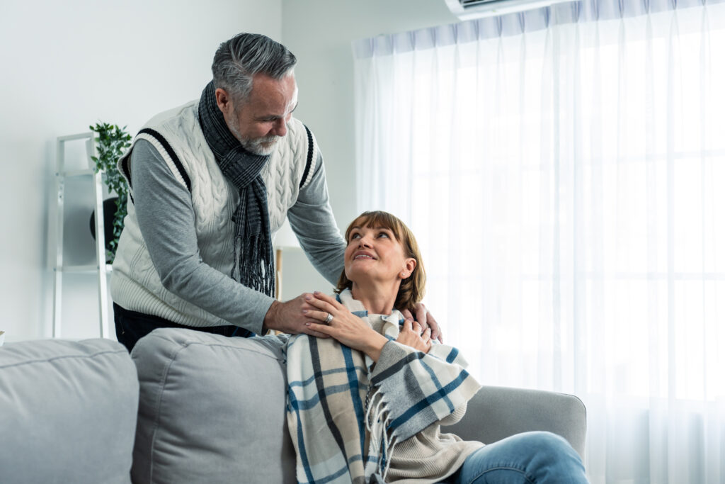 man taking care of elderly sick wife in living room