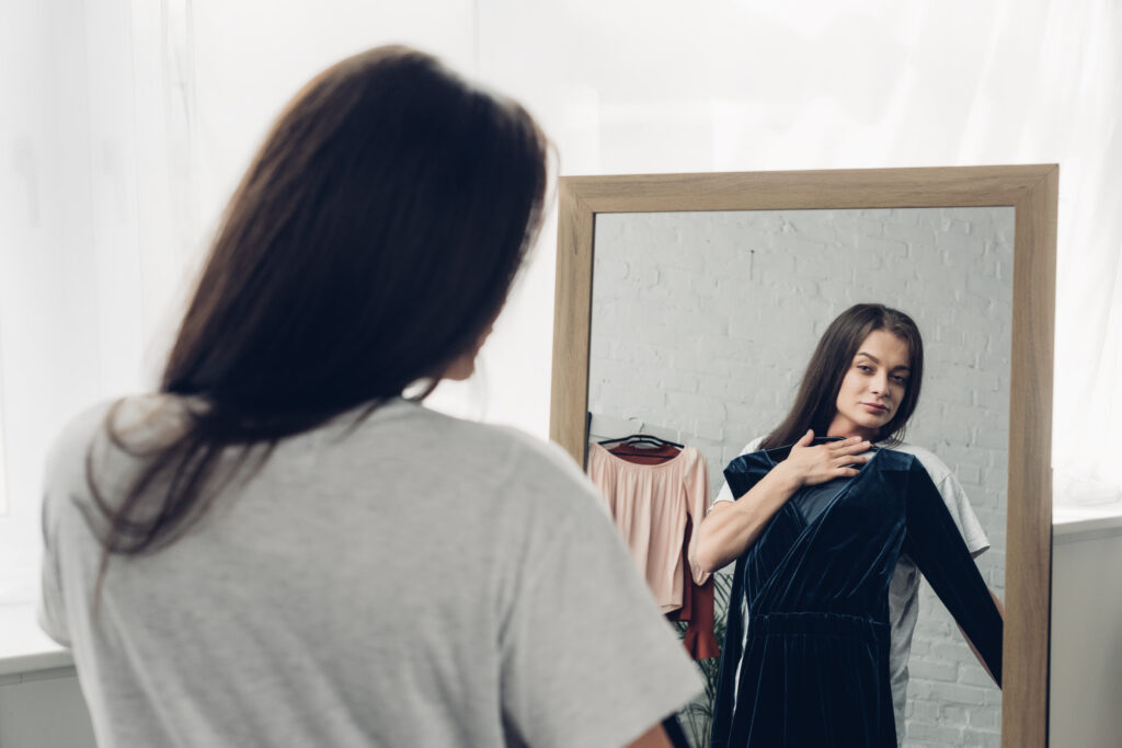 woman with dress looking at mirror at home